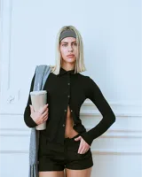 Top manga larga negro confeccionado en rayón con hilera de botones broche asimétricos.