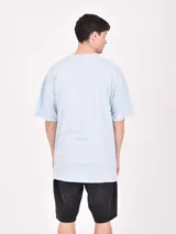 Remera blanca de corte oversized con estampado frontal de letras en color naranja y negro.