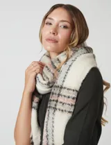 Bufandón de tejido soft, color crema con patrón a cuadros en tonos rosa pálido, gris y negro. Presenta terminación con flecos.