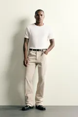 Jeans flare fit de tiro medio confeccionados en denim de algodón color beige, con cinco bolsillos, efecto salpicaduras y bajo irregular.