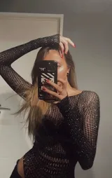 Body de red negro con mangas largas, cuello redondo y apliques de strass brillantes en toda la prenda. Presenta un diseño ajustado al cuerpo con una textura calada.