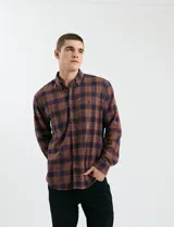 Camisa de franela a cuadros con cuello button-down, manga larga y botones de madera. Presenta dos bolsillos tipo parche en el frente con cierre de botón.