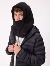 Pasamontañas de tejido tipo corderito sintético en color negro, con diseño de capucha integrada y cordones ajustables en la parte frontal.