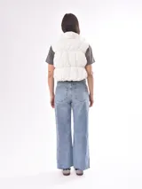 Chaleco negro con cuello alto y cierre frontal con botones a presión.