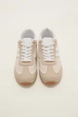 Zapatillas de estilo urbano color marrón con detalles en blanco, confeccionadas en material textil y sintético, con cordones blancos y suela de goma.