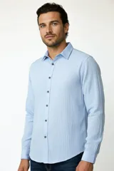 Camisa de viscosa celeste, de corte holgado, con mangas largas, cuello camisero y cierre frontal con botones oscuros.