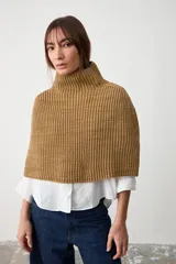 Capita de punto acanalado en color beige, con cuello alto y diseño abierto en los laterales.