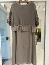 Vestido midi color gris visón, de corte recto y holgado. Cuenta con una capa superior superpuesta de tejido de punto abierto estilo red, con mangas cortas y terminaciones deshilachadas.