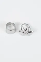 Set de dos anillos de metal plateado, uno de diseño liso y ancho con textura martillada y otro con dije en forma de estrella con relieve.