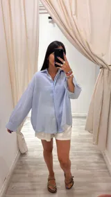 Camisa oversize color verde militar con finas rayas verticales de lurex, cuello camisero y mangas largas con puños anchos.