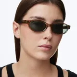 Lentes de sol con montura ovalada de color beige traslúcido y cristales polarizados en tono verde oscuro.