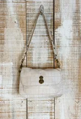 Minibag de diseño estructurado tipo acordeón, con acabado texturizado brillante en color negro. Cuenta con solapa frontal, cierre metálico giratorio y doble correa.