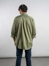 Camisa de corte regular color azul marino, confeccionada en algodón. Presenta cuello con botones, cierre frontal abotonado y un bolsillo en el pecho con el logo de la marca bordado en color rojo.