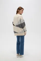Sweater de tejido de punto con diseño geométrico color block en tonos beige, gris y negro, de corte holgado, cuello redondo y manga larga.