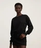 Suéter negro de punto leve, corte boxy, cuello redondo y mangas largas con puños y bajo acanalados.