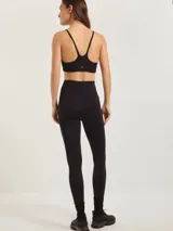 Calza deportiva negra de tiro alto, con paneles de tul transparente en la zona de los muslos y logo pequeño en la pierna.