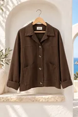 Chaqueta marrón de gabardina elastizada, con cuello camisero, cierre frontal de botones, bolsillos delanteros aplicados y mangas largas con puños doblados.