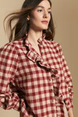 Camisa de algodón a cuadros con diseño de volados frontales, cuello alto y mangas largas con leve volumen.
