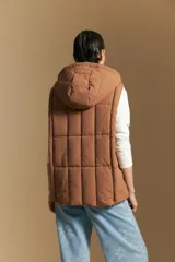 Chaleco acolchado de nylon color negro, con diseño capitoneado, capucha integrada y cierre frontal con tirador metálico.
