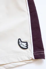 Short de baño color crema con tira lateral color borgoña y cordón de ajuste en la cintura.