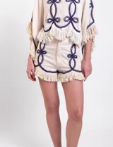 Short de algodón color beige con bordados en contraste de color azul marino y flecos en el ruedo.
