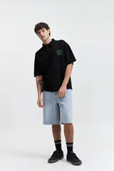 Remera polo negra de corte oversize con logo estampado en el pecho.