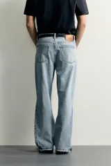 Jeans flare fit de denim negro, tiro medio, ajustados arriba y con botamanga acampanada. Cuentan con cinco bolsillos, lavado efecto gastado y bajo con acabado irregular. Cierre frontal con cremallera y botón.