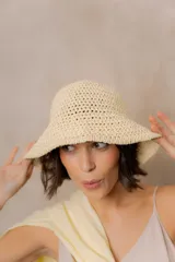 Gorro tipo bucket tejido a crochet de trama abierta, color natural, con ala corta y flexible.