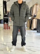 Campera puffer azul marino con capucha ajustable, cierre frontal y bolsillos laterales con cierre a presión. Cuenta con parche redondo con la inscripción "TURK" en el pecho.