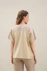 Blusa de lino de diseño contemporáneo, con escote cuadrado y mangas cortas en recortes que combinan distintas texturas. Su propuesta incorpora una franja vertical en contraste que aporta dinamismo y personalidad, mientras que el calce relajado la convierte en una prenda fresca y versátil.