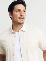 Camisa sport de manga corta, confeccionada en una mezcla de lino y algodón. Presenta cuello clásico, cierre frontal con botones de coco y un bolsillo aplicado en el pecho.