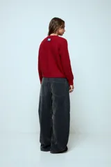 Cardigan corto de punto color rojo, con cierre frontal y cuello redondo. Presenta una textura acanalada y mangas largas.