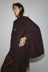 Capa de punto con cuello subido, diseño holgado y caída fluida.