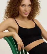 Top bralette negro de tejido seamless (sin costuras) con tirantes finos ajustables y copa desmontable. Presenta una textura sutil en el tejido.