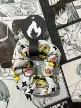 Scrunchie de tela blanca con estampado de personajes chibi de Naruto, con detalles en negro, amarillo y rojo.