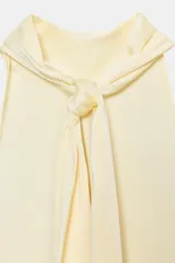 Top halter negro de tela satinada, con cuello drapeado y bajo asimétrico con caída.