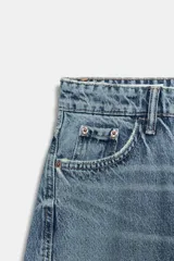 Jeans de tiro medio con corte cropped y diseño de costuras torcidas. Presenta trabillas en la cintura, cinco bolsillos clásicos y cierre frontal con cremallera y botón metálico.