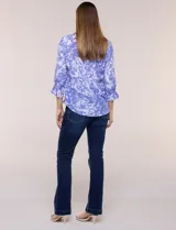 Blusa azul con estampado tipo pincelada en tonos blancos, cuello solapa con escote en V, media abotonadura frontal con botones nacarados, mangas tres cuartos con puños elásticos y diseño semi holgado.