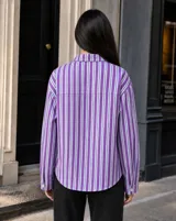Sobrecamisa de corte oversize a rayas violetas y blancas, con cuello clásico, cierre frontal de botones y bolsillos frontales.