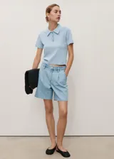 Short de jean de tiro medio con diseño recto, detalle de pinzas frontales, cierre de botón y cremallera, trabillas para cinturón y bolsillos laterales y traseros.
