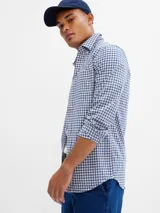 Camisa de corte slim confeccionada en tela popelina, con estampado de cuadros vichy en tonos azul y blanco. Presenta cuello clásico, cierre frontal con botones y mangas largas.