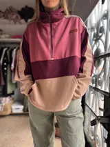 Sweater tipo canguro de diseño color block en tonos bordó, rosa y beige, con cuello alto, cierre frontal parcial y bolsillo tipo canguro.