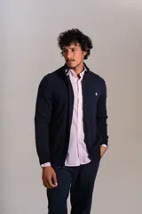 Cardigan de punto color azul marino, con cuello alto, cierre frontal completo y puños acanalados. Presenta el logo de la marca bordado en el pecho.