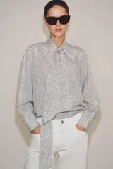 Camisa de viscosa con estampado de lunares pequeños, escote en pico con lazada frontal, manga larga y puños anchos.