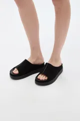 Sandalias de gamuza negra con plataforma plana, diseño de pala ancha y puntera abierta.