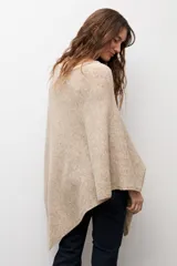 Capa tejida de corte asimétrico en tono beige, con escote redondo y diseño holgado.