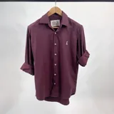 Camisa lisa color vino tinto, de manga larga con puños arremangados, cuello italiano y cierre frontal con botones.