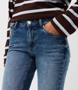 Pantalón de jean modelo bootcut con tiro bajo, ajuste en caderas y apertura sutil desde la rodilla. Cuenta con bolsillos funcionales, pasantes para cinturón y cierre frontal con botón.