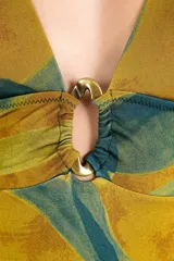 Malla enteriza estampada en tonos mostaza y verde oscuro, con escote en V profundo y detalle de argolla metálica en el centro del pecho.