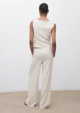 Pantalón largo color blanco crudo, de corte recto y tiro medio, con cintura elástica y cordón ajustable. Cuenta con dos bolsillos laterales.